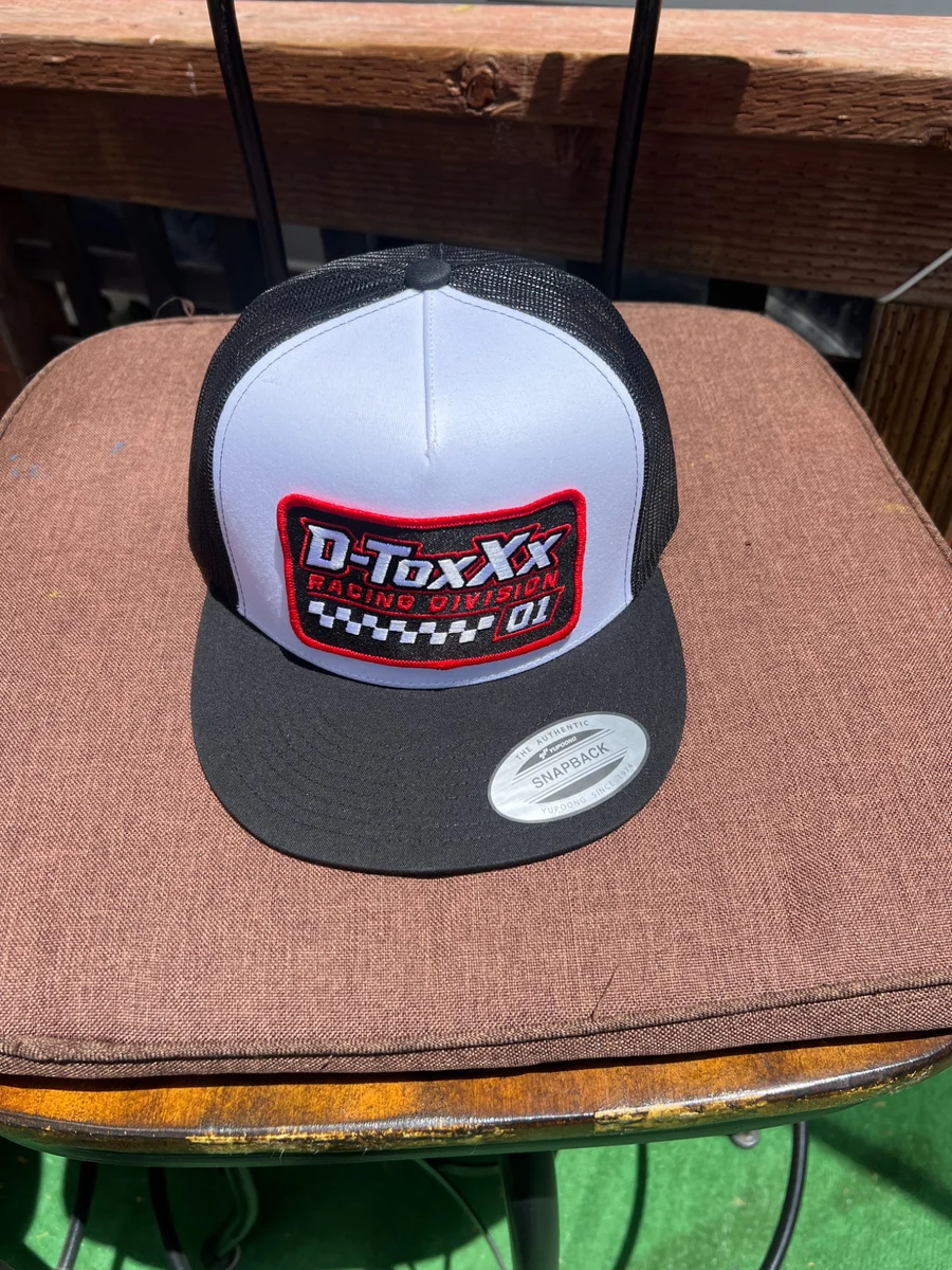 Actual original D-ToxXx white-front black-mesh snapback photographed on a chair